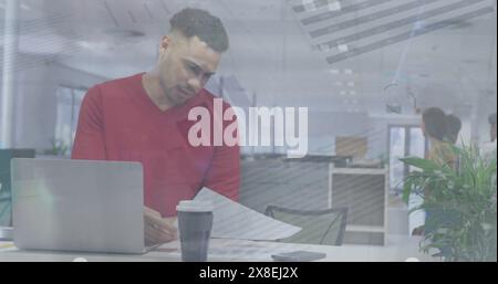 Giovane collega birazziale con capelli ricci corti e barba, in maglione rosso, studiando i documenti Foto Stock