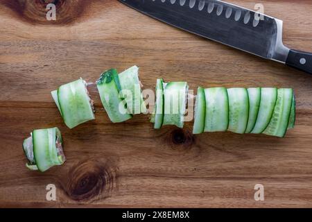 Sushi al cetriolo appena fatto tagliato in singoli rotoli, su un asse di legno. Foto Stock