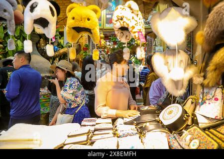 URUMQI, CINA - 24 MAGGIO 2024 - Un proprietario di stalle presenta i suoi prodotti ai clienti al Grand Bazaar Internazionale dello Xinjiang a Urumqi, nella Cina nord-occidentale" Foto Stock