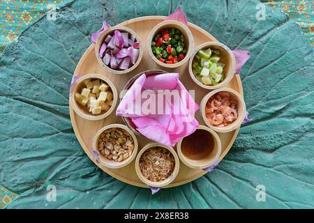 Piatto Miang kham bua lhuang dalla Thailandia con petali di fiori di loto e un'ampia varietà di ingredienti, adagiati su un tappeto decorativo Foto Stock