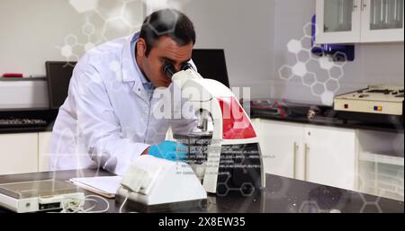 Uomo caucasico di mezza età che indossa un camice da laboratorio, che esamina i campioni al microscopio Foto Stock