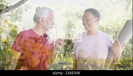 Immagine di macchie di luce e alberi su persone anziane diverse che parlano in giardino Foto Stock