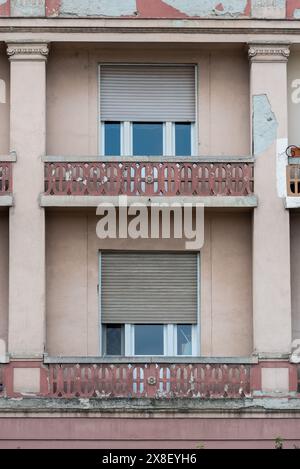 Vecchio edificio di Belgrado con finestre a tendina e balcone che mostrano segni di invecchiamento e invecchiamento. Aprile 2024. Foto Stock