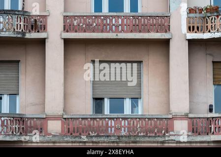 Vecchio edificio di Belgrado con finestre a tendina e balcone che mostrano segni di invecchiamento e invecchiamento. Aprile 2024. Foto Stock