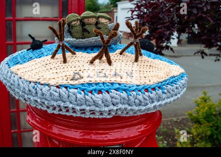 Eton Wick, Regno Unito. 25 maggio 2024. Un contenitore postale a maglia del D-Day Anniversary Post Topper nel villaggio di Eton Wick, Windsor, Berkshire. La Royal British Legion celebrerà il 80° anniversario del D-D nel Regno Unito e in Normandia il 5 e 6 giugno 2024, nonché gli eventi della comunità in tutto il Regno Unito. Chiedono ai veterani della Normandia, alle famiglie dei caduti, ai discendenti dei veterani della Normandia e ai membri del pubblico di unirsi a loro per commemorare il D-Day 80. Crediti: Maureen McLean/Alamy Live News Foto Stock