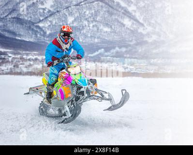 L'atleta su una motoslitta che si muove nella foresta invernale sulla gara in montagna sulla Kamchatka Foto Stock