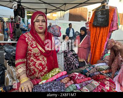 Donna che vende vestiti e vestiti alla fiera di strada del Bangladesh nella sezione di Kensington a Brooklyn, New York Foto Stock