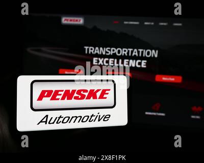 Persona che possiede uno smartphone con il logo della concessionaria statunitense Penske Automotive Group Inc. Davanti al sito Web. Mettere a fuoco il display del telefono. Foto Stock