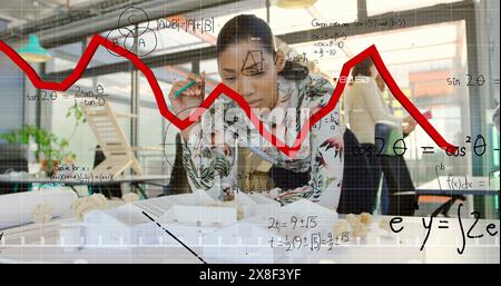Immagine di grafici rossi su una donna d'affari afroamericana che lavora su un modello in ufficio Foto Stock