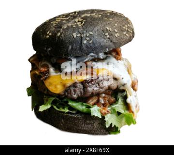 Classico cheeseburger annerito con sesamo e sottaceti. Formaggio, pomodori, cipolle. Lattuga, senape e ketchup isolati su sfondo bianco. Fresco Foto Stock