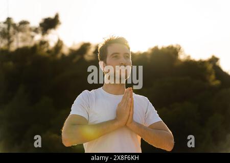 Un uomo pratica yoga in natura al tramonto Foto Stock
