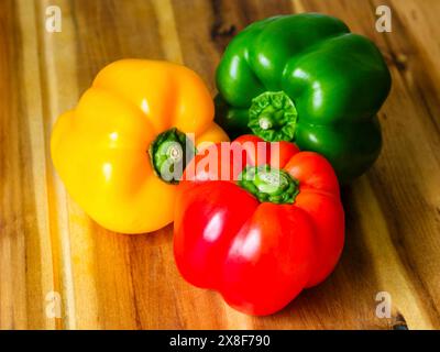 Primo piano, peperoni gialli, rossi e verdi (Capsicum annuum) su tavola di legno Foto Stock