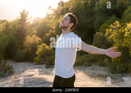 Un uomo attraente respira aria fresca dalla natura al tramonto. Stile di vita sano e benessere emotivo Foto Stock