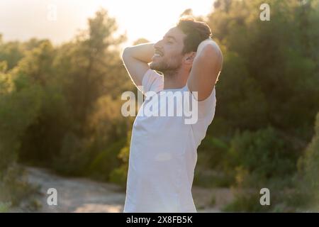 Un uomo attraente respira aria fresca dalla natura al tramonto. Stile di vita sano e benessere emotivo Foto Stock