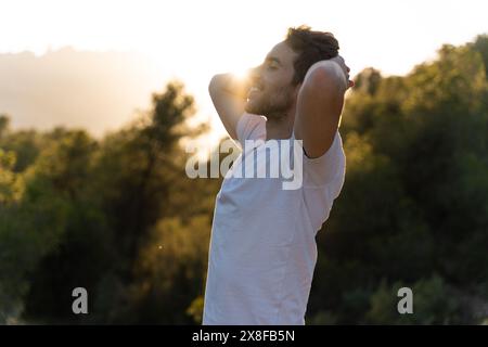 Un uomo attraente respira aria fresca dalla natura al tramonto. Stile di vita sano e benessere emotivo Foto Stock