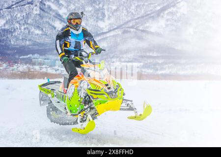 L'atleta su una motoslitta che si muove nella foresta invernale sulla pista di neve sulle montagne di Kamchatka Foto Stock