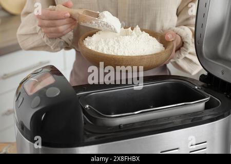 Fare l'impasto. Donna che aggiunge farina alla macchina per il pane, primo piano Foto Stock