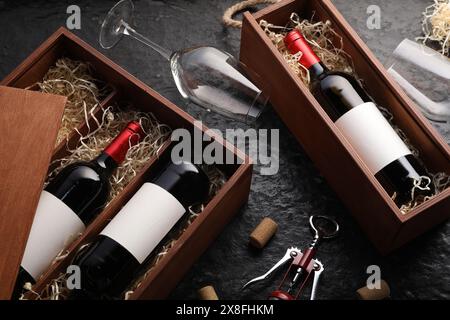 Bottiglie di vino in scatole di legno, bicchieri, cavatappi e sugheri su un tavolo a trama scura, vista dall'alto Foto Stock