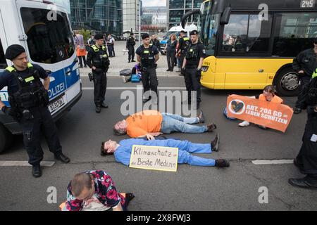 Il 25 maggio 2024, i sostenitori e gli attivisti del gruppo di attivisti per il clima "Letzte Generation" (ultima generazione) hanno creato un blocco stradale di disobbedienza civile su Rahel-Hirsch-Strasse vicino a Washingtonplatz di fronte alla stazione ferroviaria centrale di Berlino. Gli attivisti, sotto la bandiera "la protezione del clima è la protezione della democrazia”, hanno chiesto l'onestà del governo sulla crisi climatica, sottolineando che l'azione per il clima e la protesta sono parte integrante della democrazia. La polizia li ha rimossi dalla strada e ha registrato le loro informazioni personali. Diversi attivisti sono tornati ripetutamente in strada, spingendo la polica Foto Stock