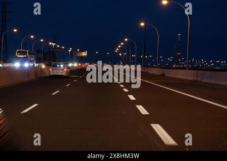 Scena notturna dell'autostrada - veicoli in movimento - lampioni illuminati - sfondo blu scuro del cielo. Presa a Toronto, Canada. Foto Stock