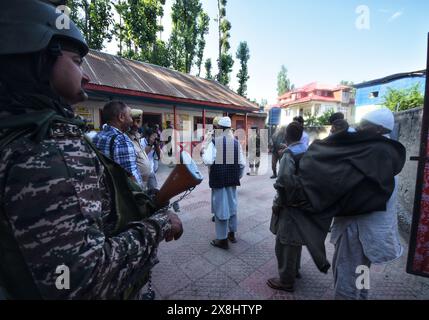 Anantnag, India. 25 maggio 2024. I soldati paramilitari decollano pehran (un tessuto tradizionale) di un vecchio uomo Kashmiri prima di votare in una stazione elettorale, durante la sesta fase elettorale, ad Anantnag, a circa 70 km da Srinagar. (Foto di Mubashir Hassan/Pacific Press) credito: Pacific Press Media Production Corp./Alamy Live News Foto Stock