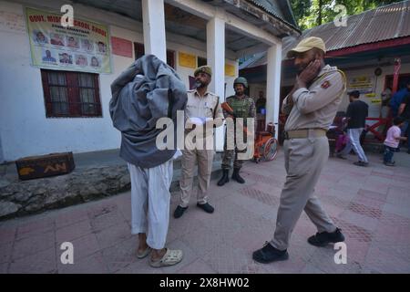 Anantnag, India. 25 maggio 2024. I soldati paramilitari decollano pehran (un tessuto tradizionale) di un vecchio uomo Kashmiri prima di votare in una stazione elettorale, durante la sesta fase elettorale, ad Anantnag, a circa 70 km da Srinagar. (Foto di Mubashir Hassan/Pacific Press) credito: Pacific Press Media Production Corp./Alamy Live News Foto Stock