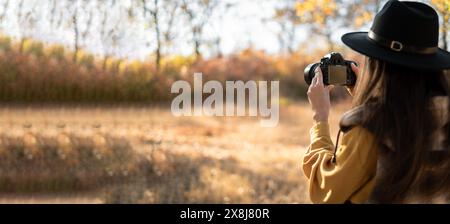 Fotografo naturalistico con fotocamera dslr nella foresta autunnale, la fotografia professionale funziona Foto Stock