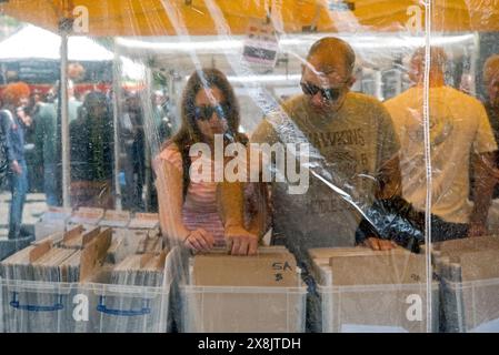 Coppia, fotografata attraverso fogli di plastica, curiosando in uno stallo del mercato del sabato a Grassmarket, Edimburgo, Scozia, Regno Unito. Foto Stock