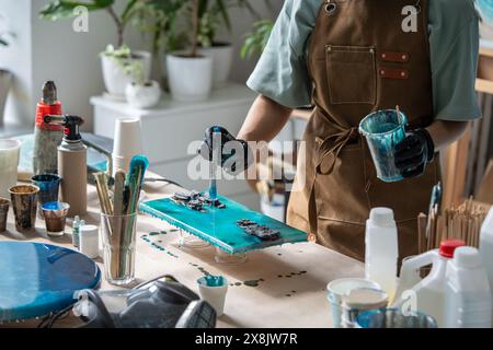 Processo di realizzazione di un primo piano artigianale utilizzando materiali moderni per la progettazione, resina epossidica liquida, legno, pietra. Foto Stock