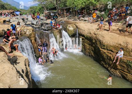 Dolores, Filippine. 25 maggio 2024: I filippini affollano torrenti che non si sono prosciugati per sfuggire al caldo soffocante delle città. A Calabarzon, alcuni trovano rifugio a Paeng Falls, una nuova destinazione creata dal tifone Paeng (2022). In streaming dal Monte Banahaw, una montagna sacra soggetta a frane, erosione e alluvioni distruttive, il letto del fiume Lagnas si è placato per formare queste cascate molto apprezzate in quanto l'arcipelago e il sud-est asiatico soffrono di forti ondate di caldo e siccità a causa di El Nino che terminerà con la depressione tropicale Aghon, la prima tempesta a colpire il paese quest'anno. Crediti: Kevin Izorce/Alamy Live News Foto Stock