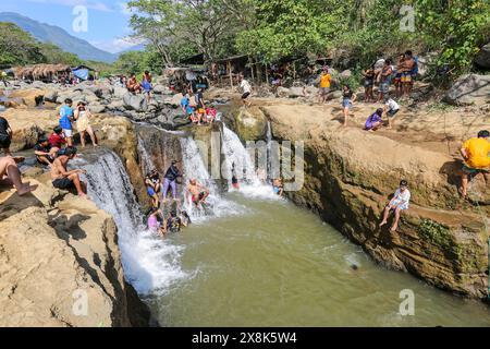 Dolores, Filippine. 25 maggio 2024: I filippini affollano torrenti che non si sono prosciugati per sfuggire al caldo soffocante delle città. A Calabarzon, alcuni trovano rifugio a Paeng Falls, una nuova destinazione creata dal tifone Paeng (2022). In streaming dal Monte Banahaw, una montagna sacra soggetta a frane, erosione e alluvioni distruttive, il letto del fiume Lagnas si è placato per formare queste cascate molto apprezzate in quanto l'arcipelago e il sud-est asiatico soffrono di forti ondate di caldo e siccità a causa di El Nino che terminerà con la depressione tropicale Aghon, la prima tempesta a colpire il paese quest'anno. Crediti: Kevin Izorce/Alamy Live News Foto Stock