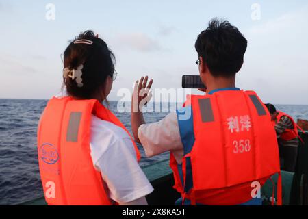 (240526) -- SANYA, 26 maggio 2024 (Xinhua) -- la gente saluta la balena pilota a pinna corta "Haitang" su una nave di ricerca scientifica, 26 maggio 2024. Il 3 gennaio di quest'anno, un pilota di balena a pinna corta maschio ferito è stato trovato bloccato nella baia di Haitang di Sanya. È stato inviato al Sanya Haichang Animal Conservation Center per il trattamento ed è stato chiamato "Haitang". Grazie alla meticolosa cura fornita da allevatori professionisti e volontari, "Haitang" si riprende bene ed è determinato a essere rimesso in mare dopo un esame approfondito e una valutazione da parte di esperti. (Xinhua/Zhang Liy Foto Stock