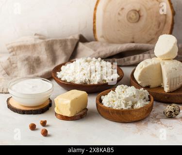 Prodotti lattiero-caseari assortiti, tra cui formaggio fresco, panna acida e burro su un ambiente rustico in legno Foto Stock