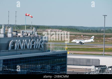 Helsinki / Finlandia - 19 MAGGIO 2024: Vista artistica del logo della compagnia di bandiera finlandese Finnair. Un aereo Airbus che decolla sullo sfondo. Foto Stock