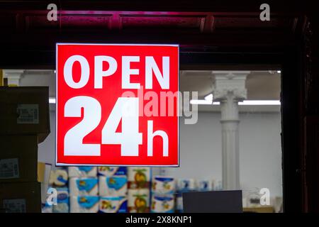Cartello rosso "aperto 24 ore" appeso fuori dalla vetrina di un negozio. Foto Stock