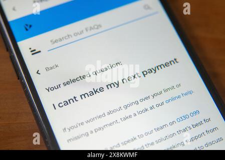 Schermata del telefono cellulare che visualizza una pagina delle domande frequenti sui fondi insufficienti per il pagamento, evidenziando le difficoltà finanziarie e le opzioni di assistenza Foto Stock