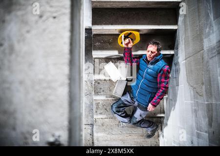 Lavoratore uomo steso sulle scale dopo la caduta. Infortunio sul lavoro, infortunio sul posto di lavoro. Foto Stock