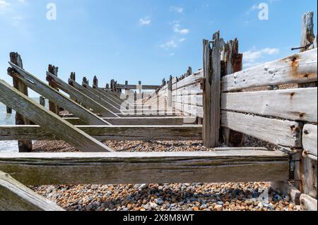 Vecchie difese marittime in legno e frangiflutti a Rye Harbour con pesanti travi di supporto diagonali e orizzontali, danneggiate e usurate dal mare. Foto Stock