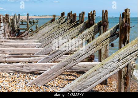 Vecchie difese marittime in legno e frangiflutti a Rye Harbour con pesanti travi di supporto diagonali e orizzontali, danneggiate e usurate dal mare. Foto Stock