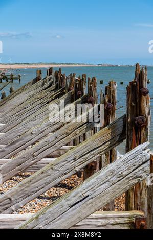 Vecchie difese marittime in legno e frangiflutti a Rye Harbour con pesanti travi di supporto diagonali e orizzontali, danneggiate e usurate dal mare. Foto Stock