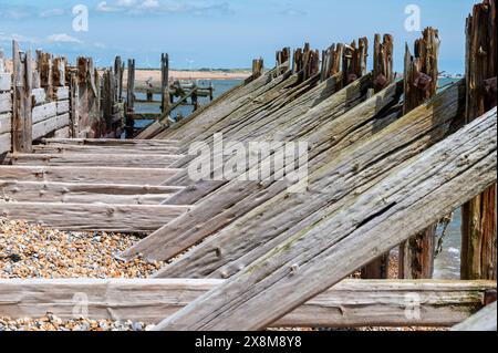 Vecchie difese marittime in legno e frangiflutti a Rye Harbour con pesanti travi di supporto diagonali e orizzontali, danneggiate e usurate dal mare. Foto Stock