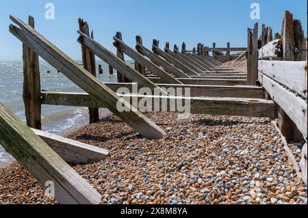 Vecchie difese marittime in legno e frangiflutti a Rye Harbour con pesanti travi di supporto diagonali e orizzontali, danneggiate e usurate dal mare. Foto Stock