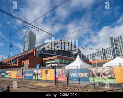 Manchester Regno Unito 26 maggio 2024. Paesaggio urbano di edifici moderni e alti edifici a Manchester con gru da costruzione e accoglienti striscioni sotto il cielo blu Foto Stock