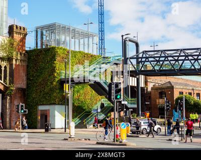 Manchester Regno Unito 26 maggio 2024. Vivace scena cittadina con verdi giardini verticali, architettura moderna, traffico intenso e pedoni in una giornata di sole Foto Stock