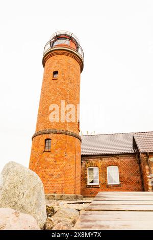 Un edificio in mattoni con un faro che si erge maestosamente in cima, attirando l'attenzione con il suo faro. La struttura è caratterizzata da mattoni e finestre sotto Foto Stock