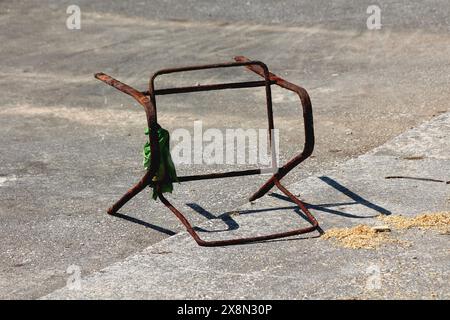 Telaio in metallo della sedia da spiaggia completamente arrugginito rotto con vecchia t-shirt verde fatiscente avvolta intorno al mare dopo aver pulito la spazzatura dell'oceano Foto Stock