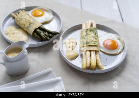 Asparagi verdi e bianchi avvolti in crepe, accanto all'uovo fritto. Gli asparagi, che rappresentano le fibre alimentari, sono molto popolari in Germania durante Spargelzeit Foto Stock