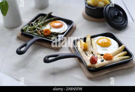 Asparagi verdi e bianchi serviti con pomodori, uova fritte, patate bollite. Questo piatto di stagione è molto popolare in Germania durante lo Spargelzeit Foto Stock