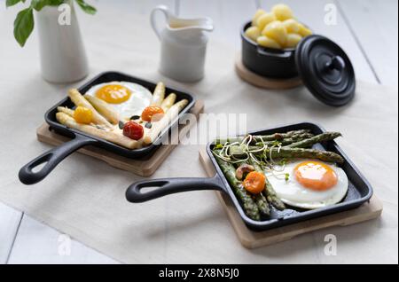 Asparagi verdi e bianchi serviti con pomodori, uova fritte, patate bollite. Questo piatto di stagione è molto popolare in Germania durante lo Spargelzeit Foto Stock