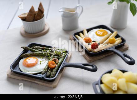 Asparagi verdi e bianchi serviti con pomodori, uova fritte, patate bollite. Questo piatto di stagione è molto popolare in Germania durante lo Spargelzeit Foto Stock